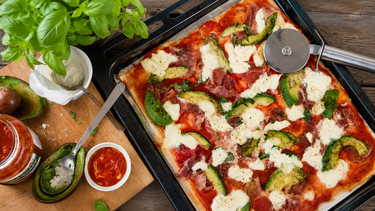 Pizza met parmaham, avocado, mozzarella, crème fraîche en bascilicum